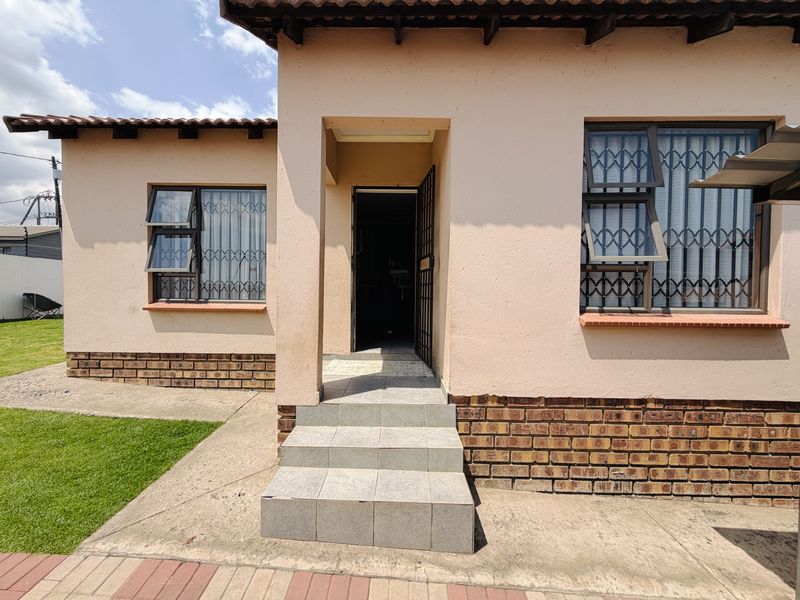 Front entrance of a single-story house featuring tiled steps, security gates, and brick plinth detailing.
