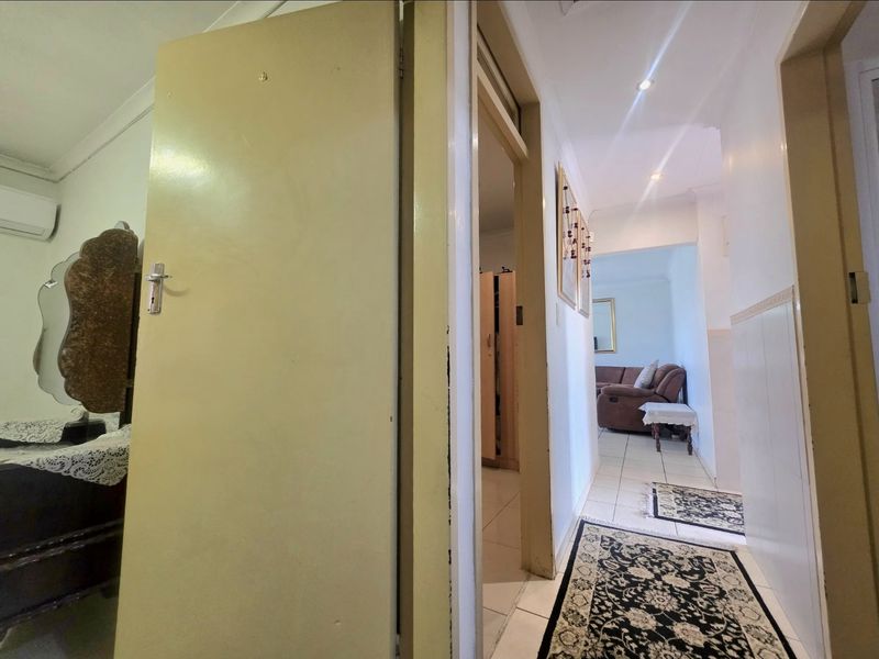 A functional hallway connecting multiple rooms, featuring tiled flooring and recessed downlighting throughout the transition space.