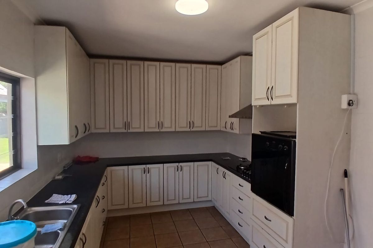 A functional kitchen featuring white cabinetry, black granite countertops, a built-in oven, gas hob, and tiled flooring.