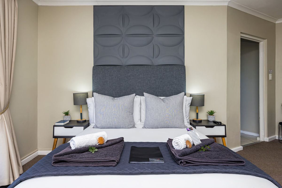 A well-presented bedroom featuring a modern decorative wall panel feature behind the bed and classic coving detail.