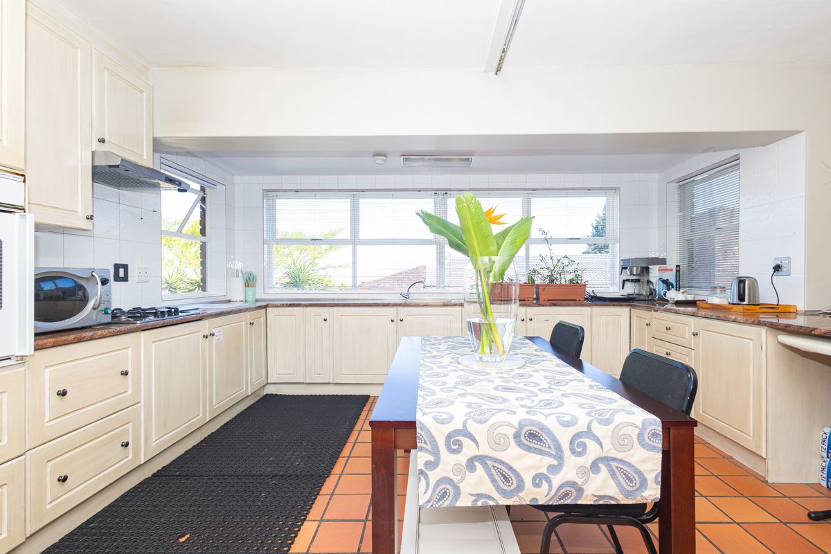 Spacious kitchen featuring ample built-in cabinetry, laminate countertops, gas hob, extractor fan, and tiled flooring with a functional layout.