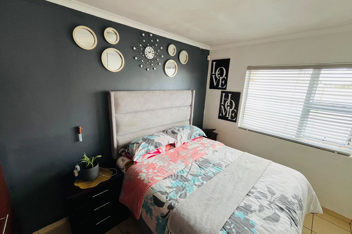 A bedroom featuring tiled flooring and venetian blinds, with a dark accent wall providing a focal point for the space.