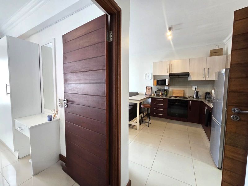 A functional kitchen featuring dark and light wood cabinetry, granite countertops, built-in oven, and extractor fan, finished with neutral ceramic floor tiles.