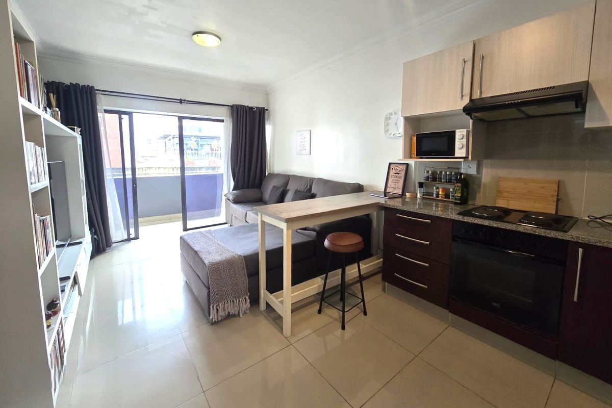Open-plan living area featuring a modern kitchen with built-in cabinetry, granite countertops, and direct access to a private balcony through sliding glass doors.