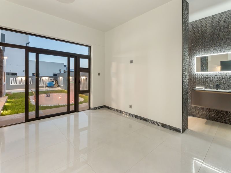Modern open-plan living space featuring large sliding glass doors, polished porcelain flooring, and a sleek integrated vanity area with contemporary lighting.