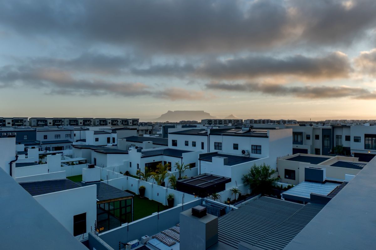 An elevated aerial view of a modern residential estate featuring contemporary flat-roofed homes with a distant mountain view.