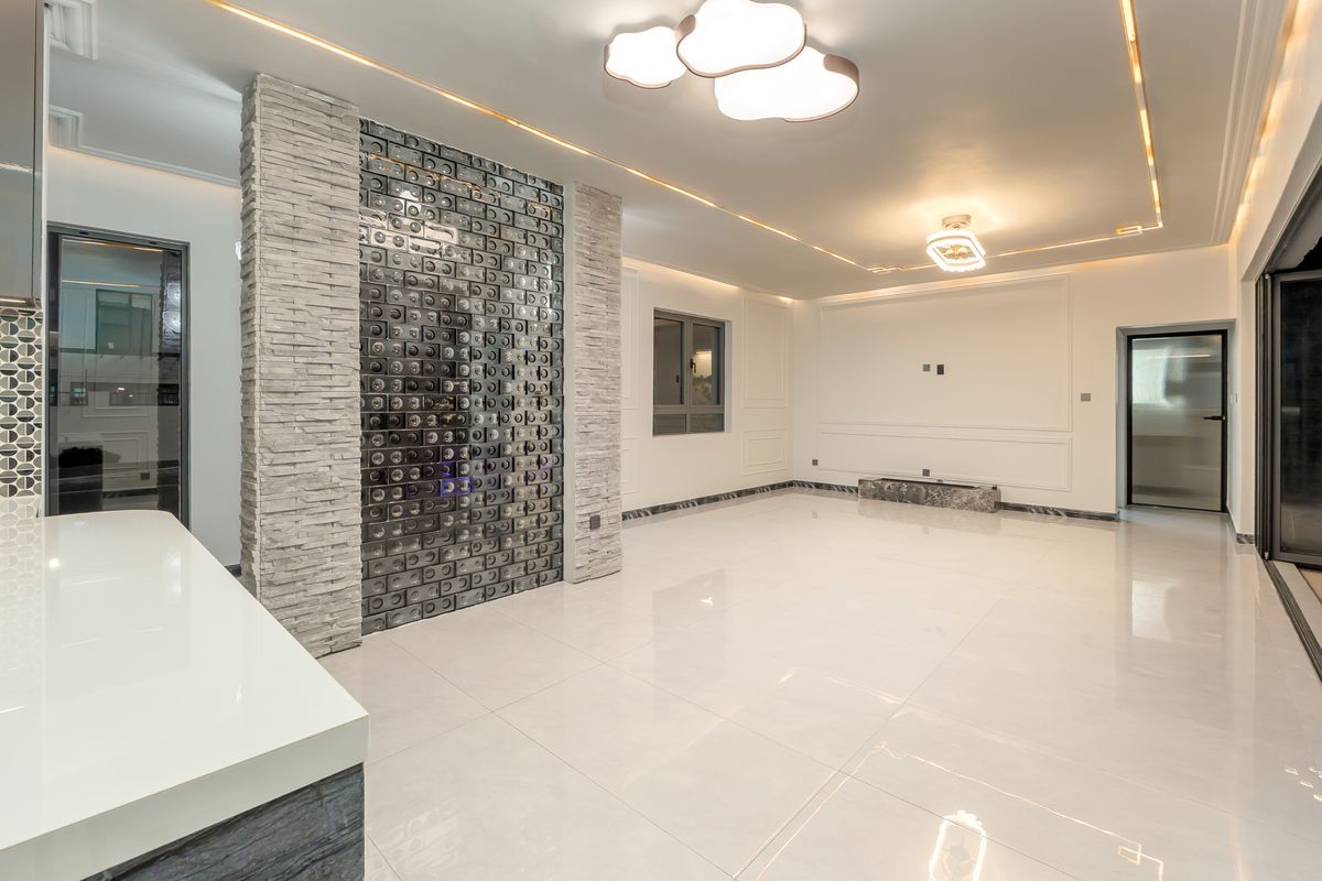 Spacious living area featuring elegant porcelain flooring, decorative stone and glass block feature walls, recessed ceiling lighting, and sophisticated wainscoting details.