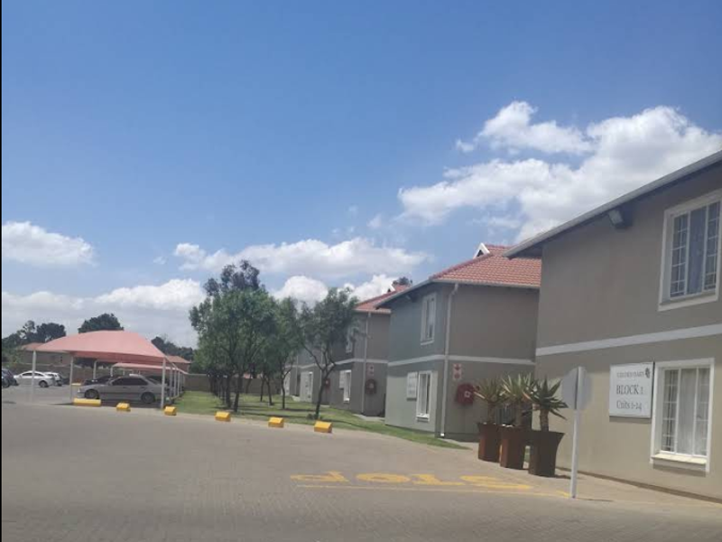 Exterior view of the apartment complex featuring paved parking areas, covered carports, and well-maintained building facades.