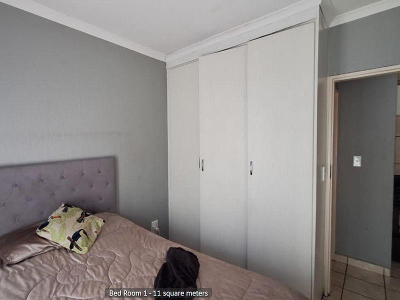 A bedroom featuring a built-in wardrobe with white sliding doors and grey painted walls, providing functional storage space.