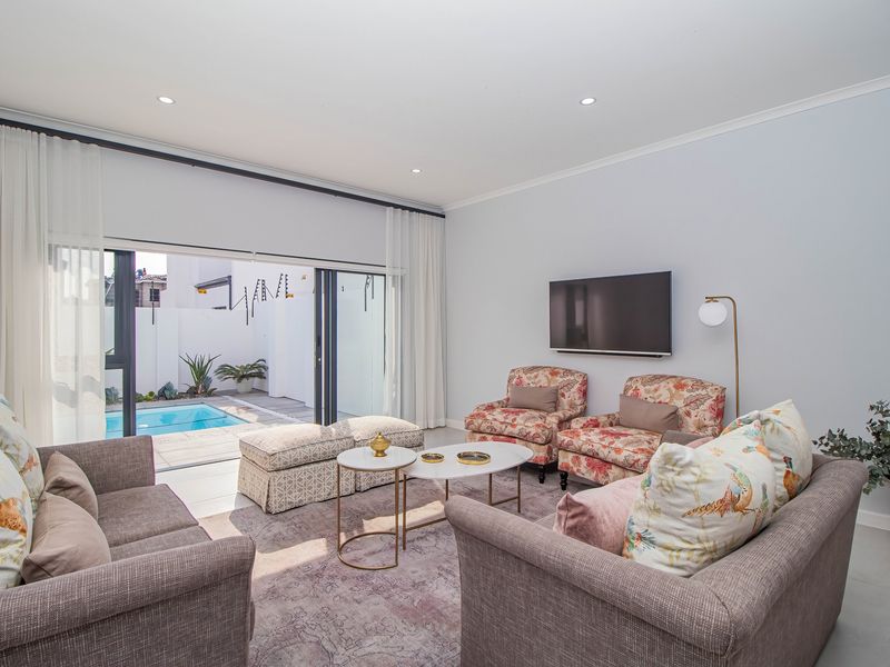 Bright and modern living room featuring large sliding glass doors that open directly onto a private pool area, creating a seamless indoor-outdoor flow.