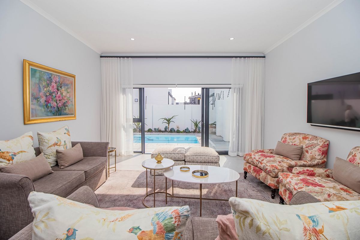 Bright living room featuring large sliding glass doors that open directly onto a private swimming pool area.