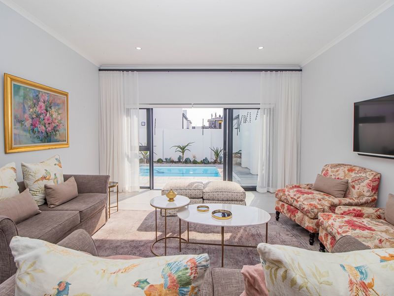 Bright living room featuring large sliding glass doors that open directly onto a private swimming pool area.