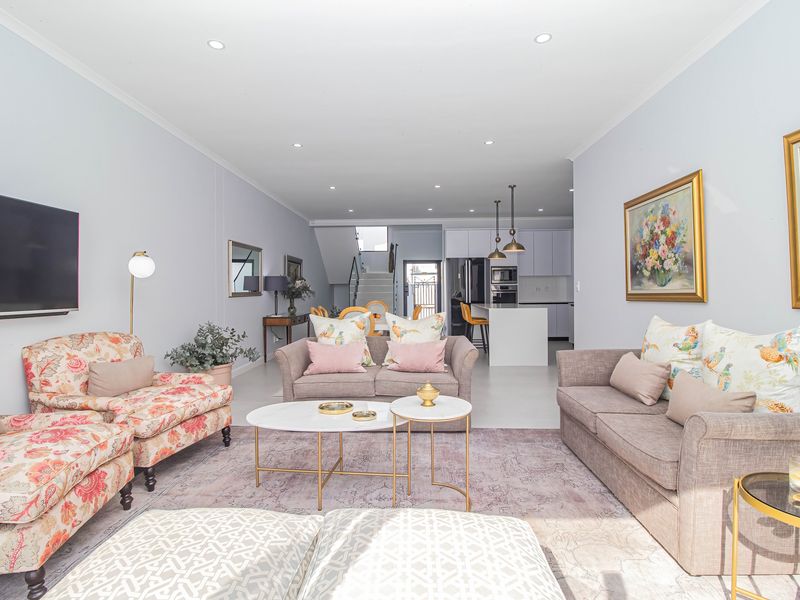 Spacious open-plan living area featuring a modern kitchen with an island, recessed lighting, and a staircase leading to the upper level.