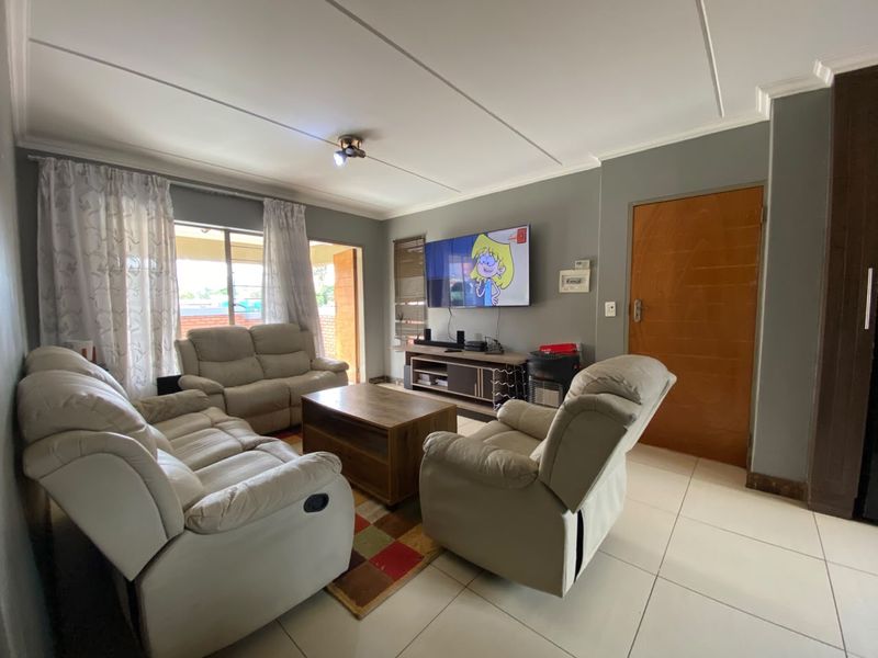 A comfortable living room featuring tiled flooring, neutral wall tones, and direct access to an outdoor area through a sliding door.