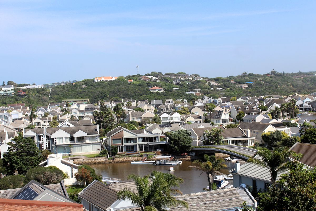 An elevated panoramic view overlooking a residential estate, river, and bridge, showcasing the surrounding neighborhood and landscape.