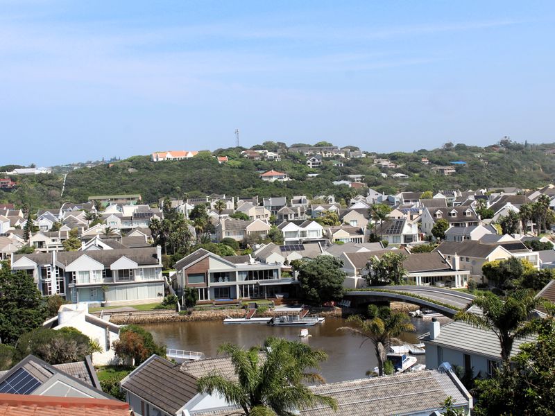 An elevated panoramic view overlooking a residential estate, river, and bridge, showcasing the surrounding neighborhood and landscape.