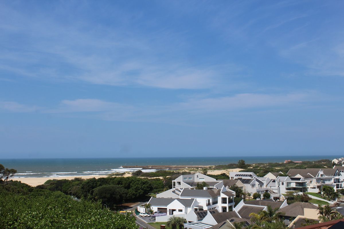 A scenic elevated view overlooking a coastal residential neighborhood with direct access to the beach and ocean.