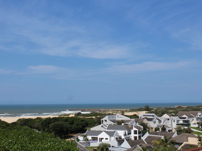 A scenic elevated view overlooking a coastal residential neighborhood with direct access to the beach and ocean.