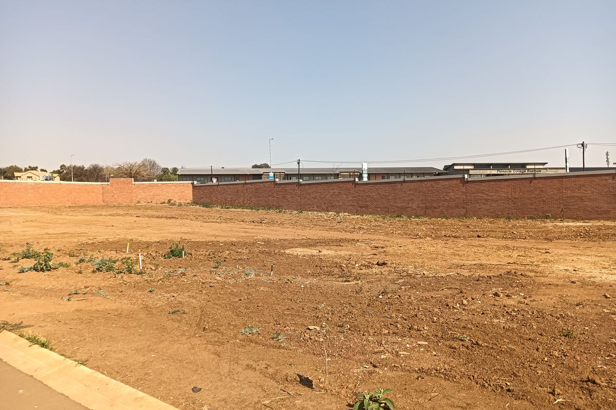 A vacant residential plot featuring a level surface and a perimeter brick boundary wall, ready for development.