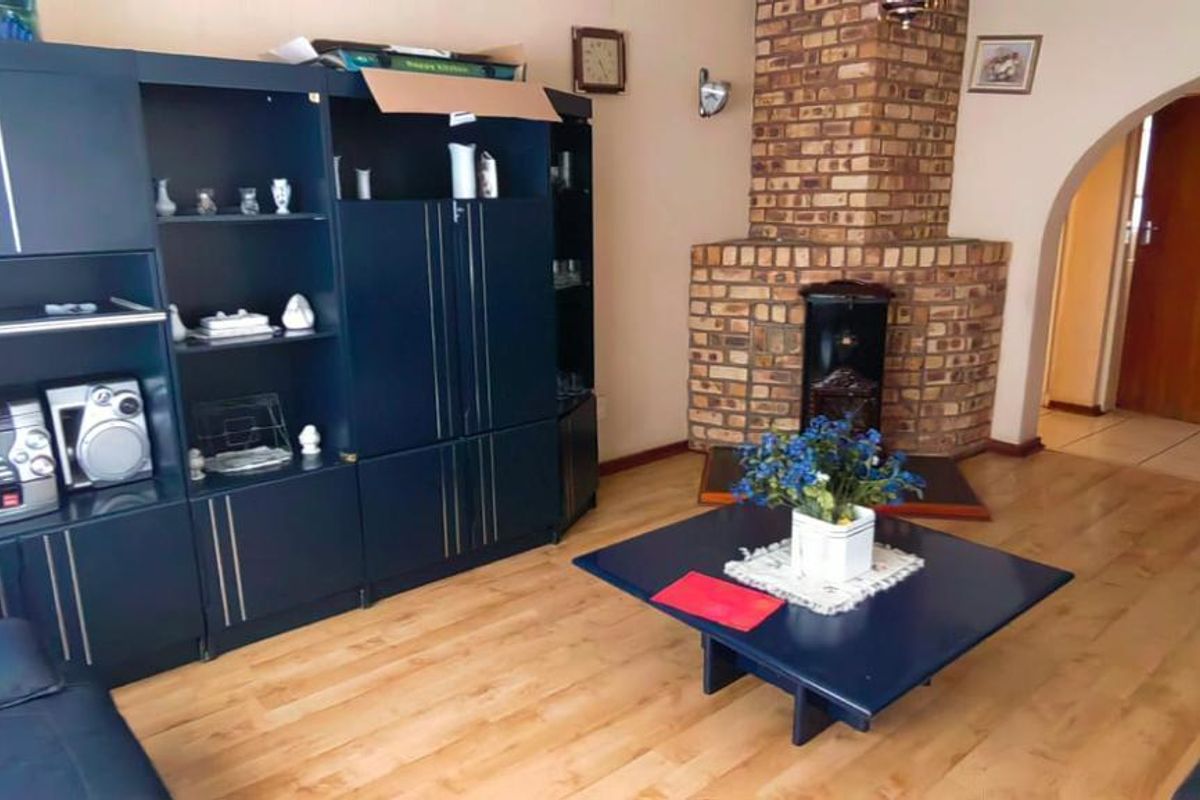 A living room featuring a prominent brick fireplace, laminate flooring, and an arched entryway leading to an adjacent space.