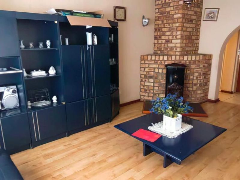 A living room featuring a prominent brick fireplace, laminate flooring, and an arched entryway leading to an adjacent space.