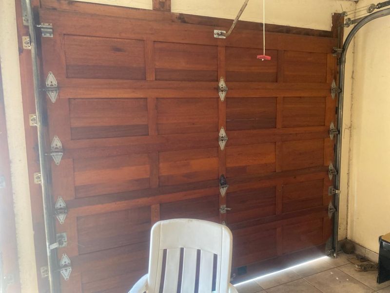 Interior view of a garage featuring a sectional timber door with visible wear and metal hardware showing signs of surface rust.