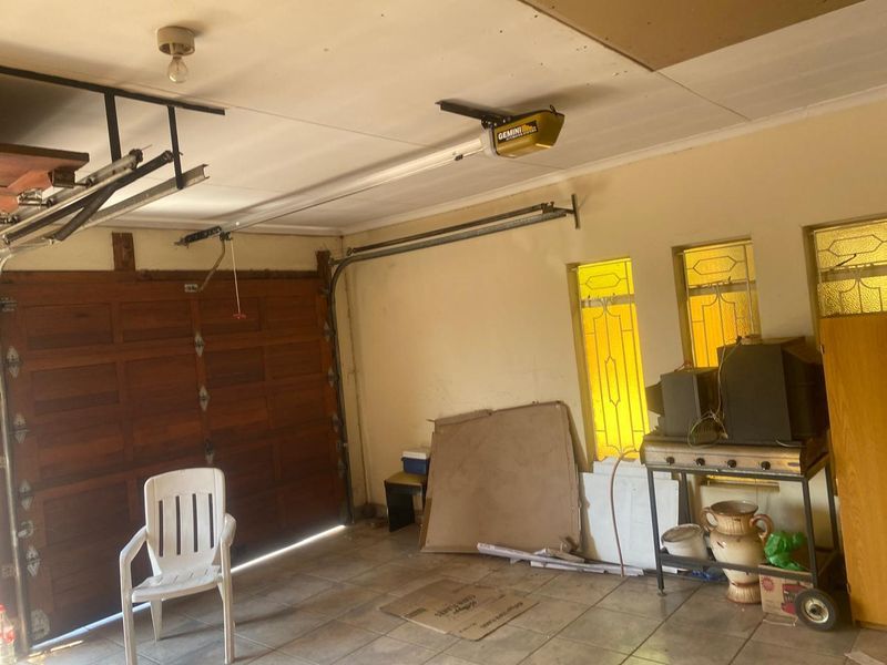 A functional garage space featuring a sectional timber door, automatic opener, tiled flooring, and decorative leaded glass windows.