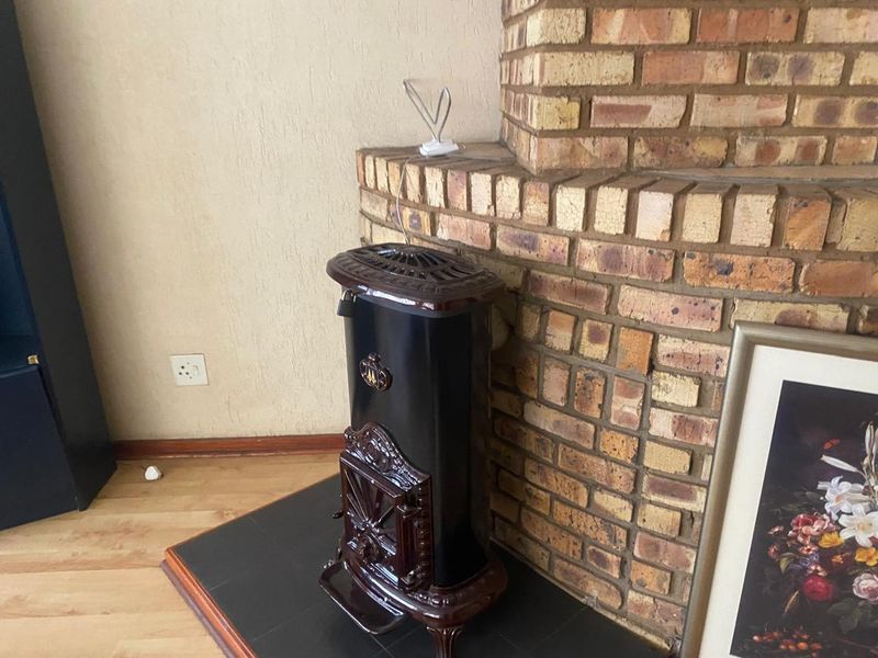 A living room area featuring a traditional brick fireplace with a black cast iron stove set on a tiled hearth.