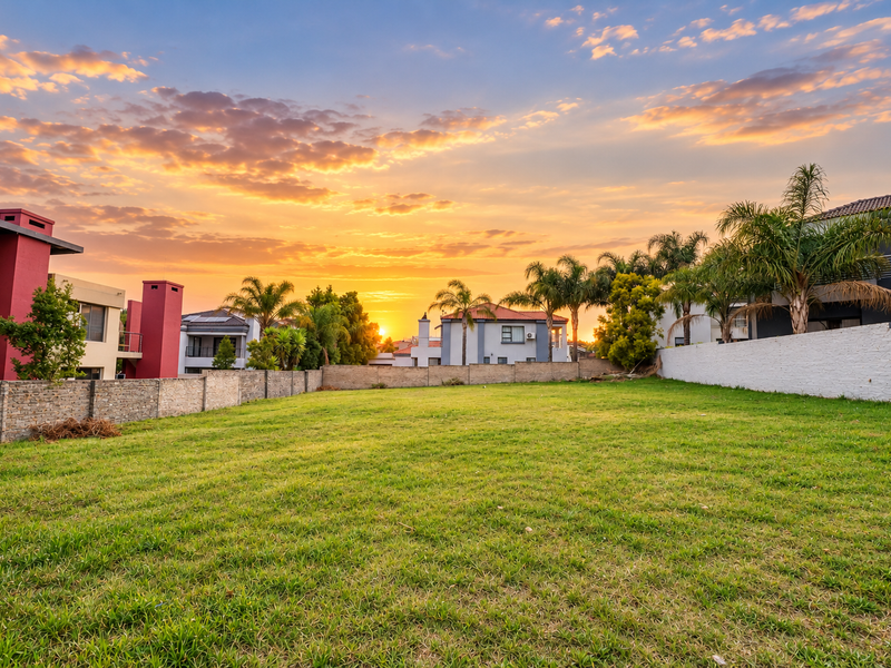 A spacious, well-maintained vacant residential plot featuring a manicured lawn and secure boundary walls, situated within a developed residential estate.
