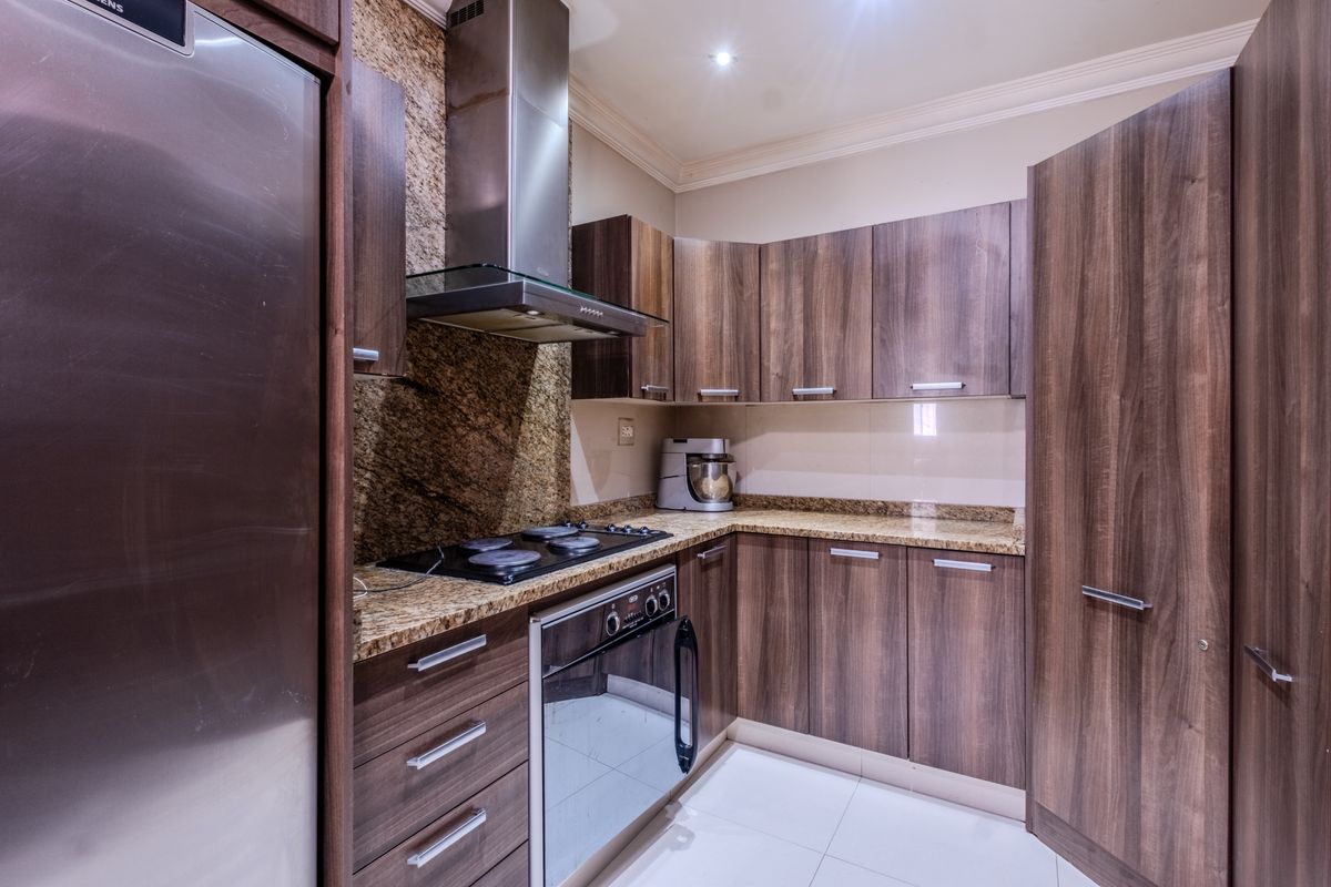 Modern kitchen featuring dark wood cabinetry, granite countertops, stainless steel appliances, and tiled flooring, offering a functional and well-maintained cooking space.