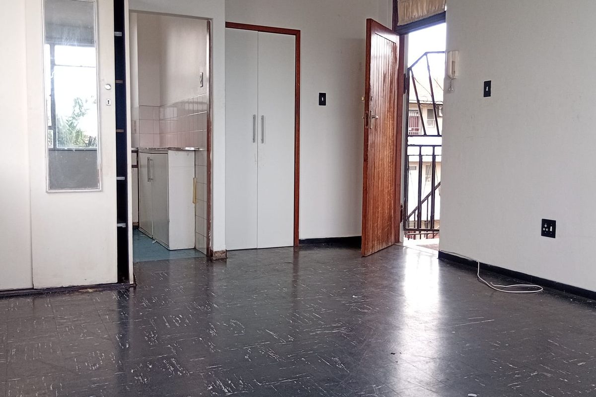 An empty living area featuring tiled flooring, built-in storage cupboards, and direct access to an outdoor balcony space.