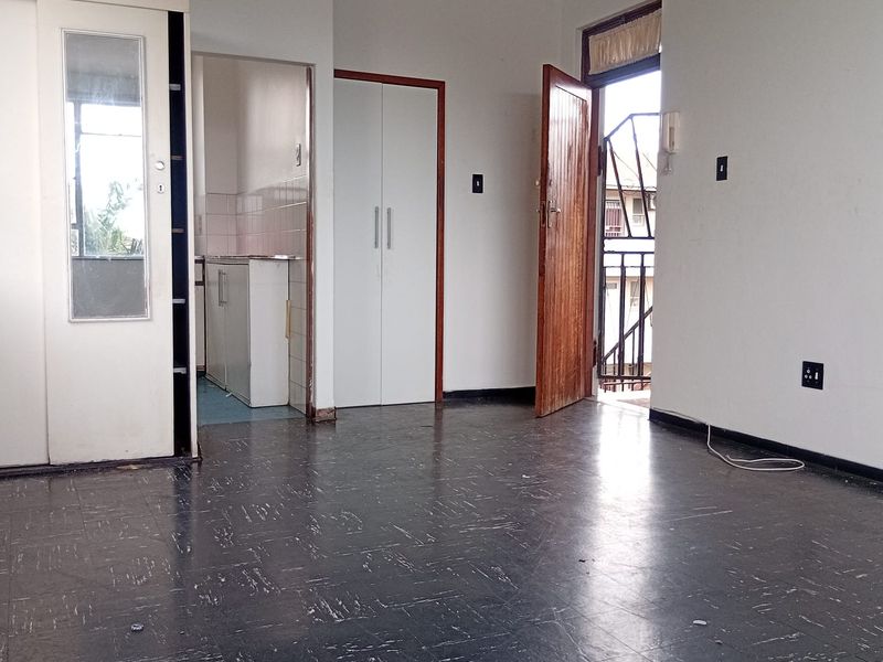 An empty living area featuring tiled flooring, built-in storage cupboards, and direct access to an outdoor balcony space.