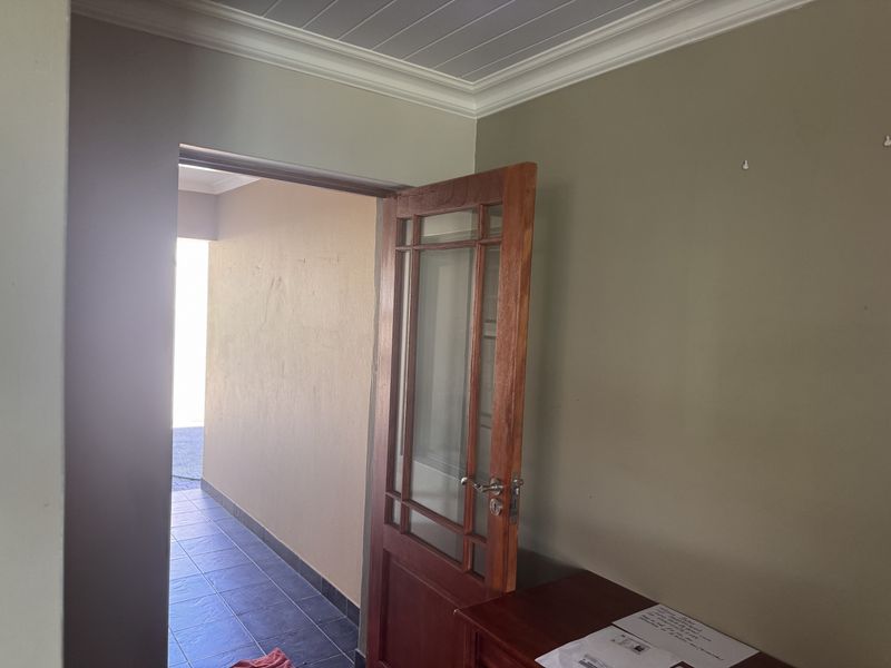 A transition space featuring a timber framed glass door, decorative ceiling cornice, and tongue and groove ceiling paneling.