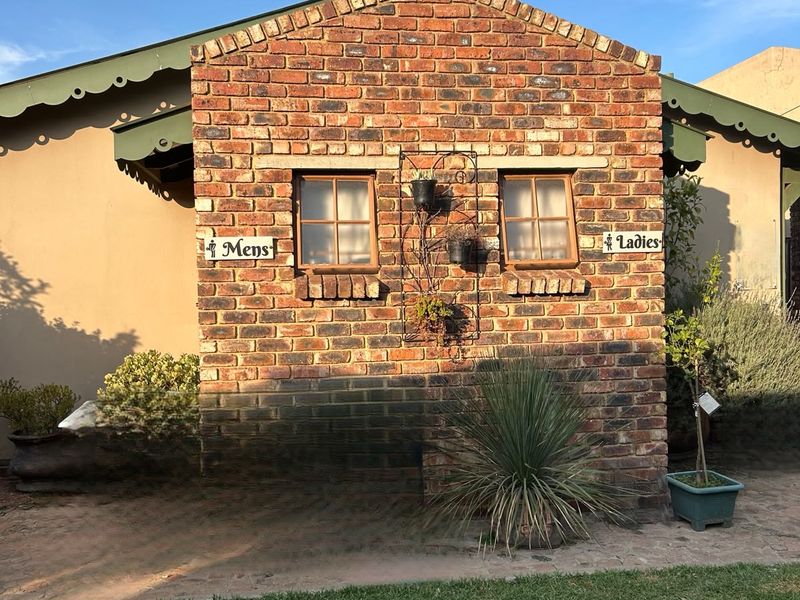 A charming exterior view of a brick-clad outbuilding featuring timber-framed windows and decorative eaves, set within a well-maintained garden area.