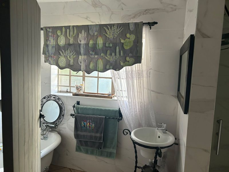 A bathroom featuring marble-look wall tiles, a pedestal sink, and a classic clawfoot bathtub, offering a blend of traditional and modern finishes.