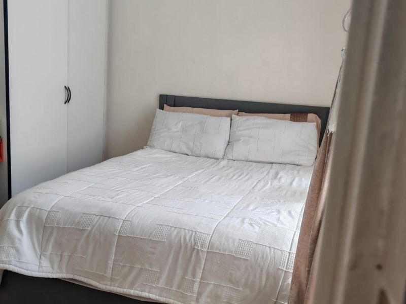 A functional bedroom featuring a built-in wardrobe and tiled flooring, offering a clean and simple living space.