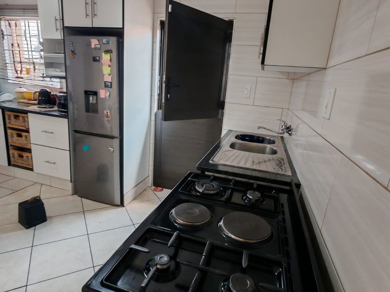 A functional kitchen featuring built-in cabinetry, a gas hob with extractor fan, double sink, and tiled finishes with a convenient stable door.