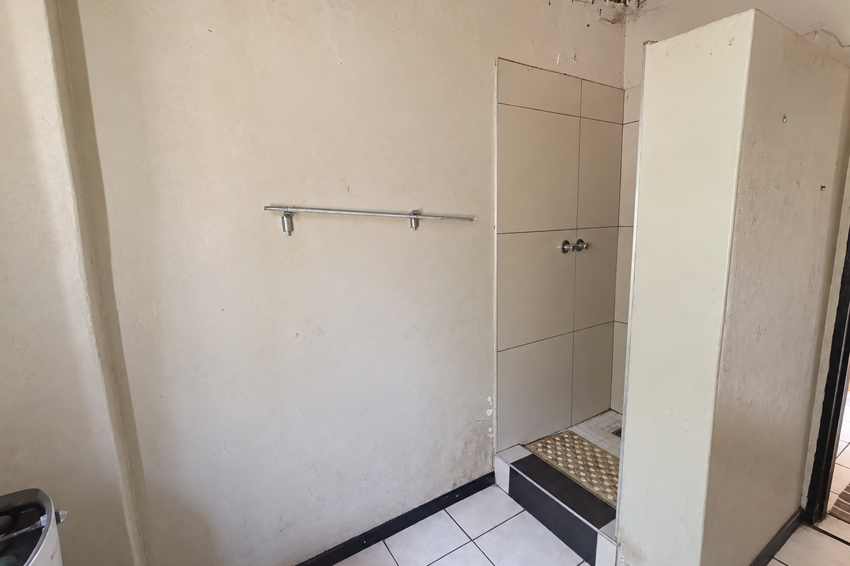A bathroom featuring a tiled shower enclosure and tiled flooring, currently requiring repairs to the ceiling and wall finishes.