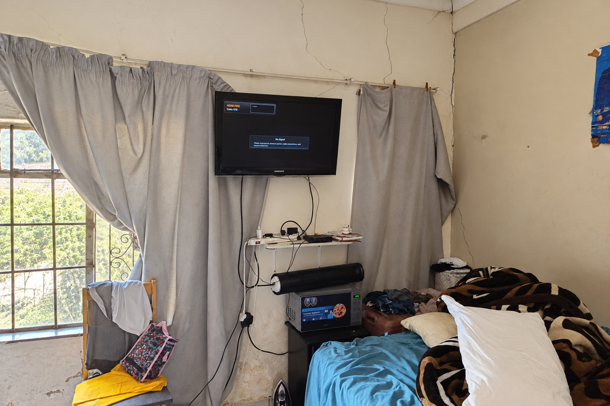 Bedroom featuring a steel-framed window and visible structural wall cracking requiring maintenance and cosmetic repair.