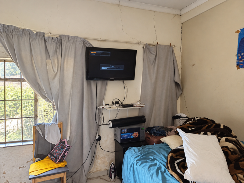 Bedroom featuring a steel-framed window and visible structural wall cracking requiring maintenance and cosmetic repair.