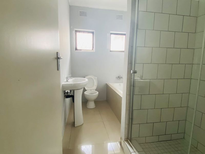 A functional bathroom featuring a pedestal basin, toilet, bathtub, and a separate shower enclosure with white subway tiling.