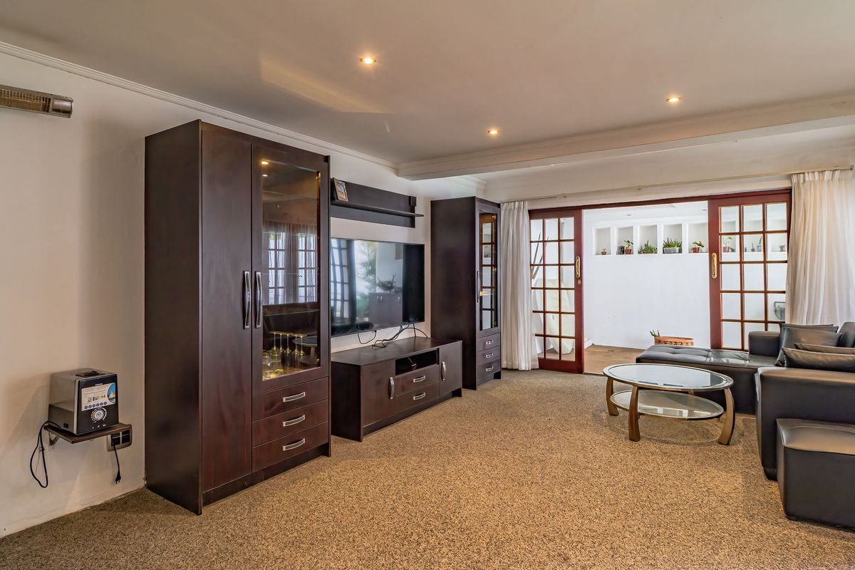 Spacious living room featuring recessed lighting, carpeted flooring, and double french doors providing access to an adjoining outdoor area.