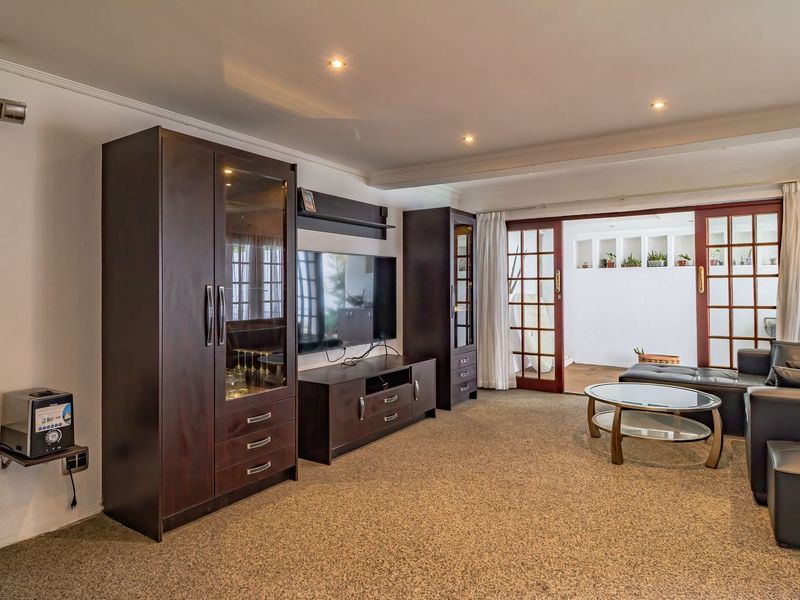 Spacious living room featuring recessed lighting, carpeted flooring, and double french doors providing access to an adjoining outdoor area.