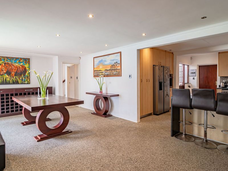 Spacious open-plan living and dining area featuring a modern kitchen with breakfast bar, built-in cabinetry, and integrated wine storage.