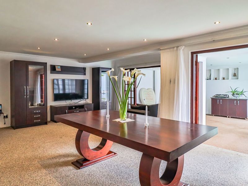 Spacious open-plan living and dining area featuring recessed lighting, carpeted floors, and seamless access to an adjoining covered patio space.