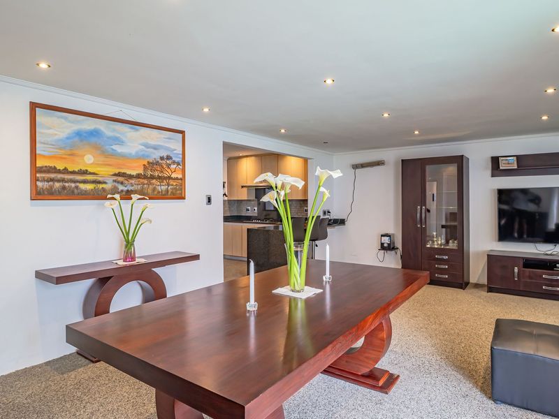 Spacious open-plan living and dining area featuring recessed lighting and a seamless transition to a functional kitchen with granite countertops.