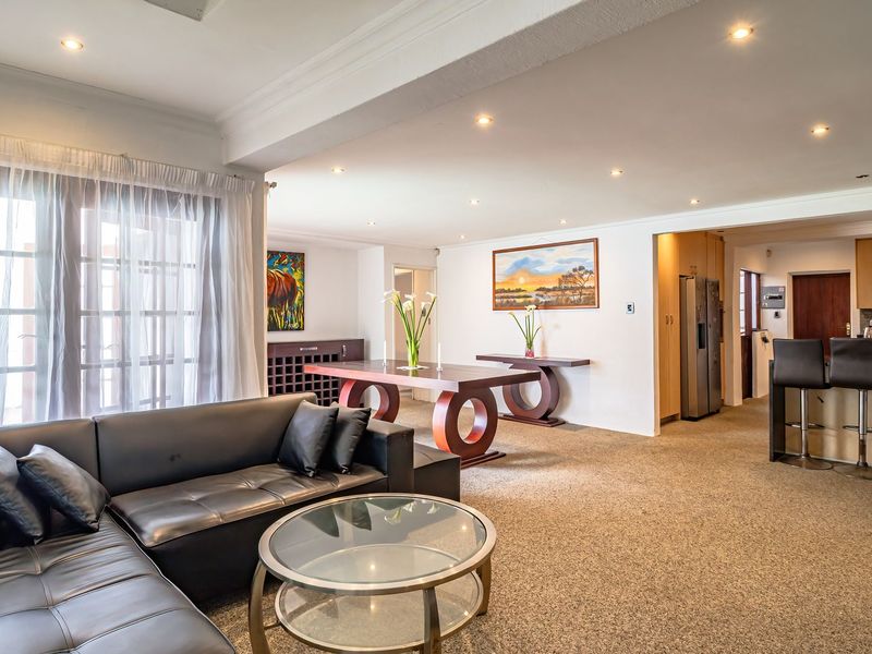 Spacious open-plan living and dining area featuring a functional kitchen with breakfast bar, recessed lighting, and direct access to the outdoor space.