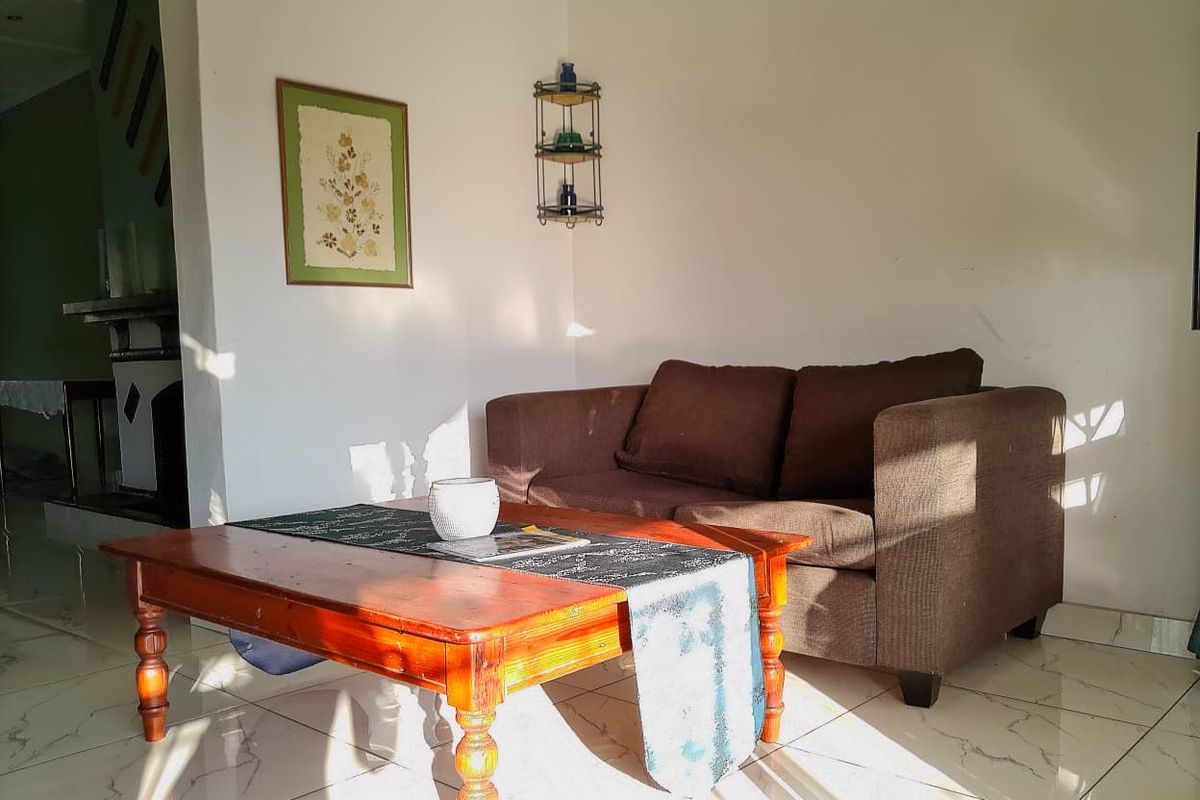 A living room area featuring tiled flooring and a fireplace, receiving natural light.