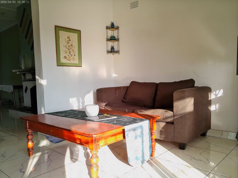 A living room area featuring tiled flooring and a fireplace, receiving natural light.