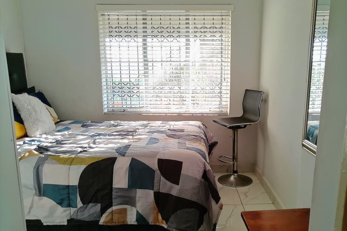 A compact bedroom featuring tiled flooring and venetian blinds, providing a functional space with natural light.